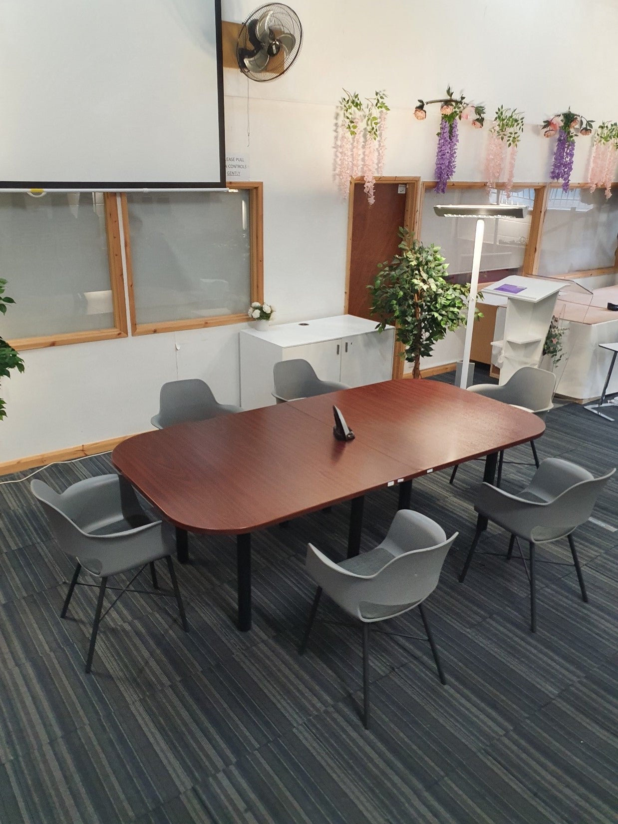 A meeting table in a large hall six grey chairs encompass