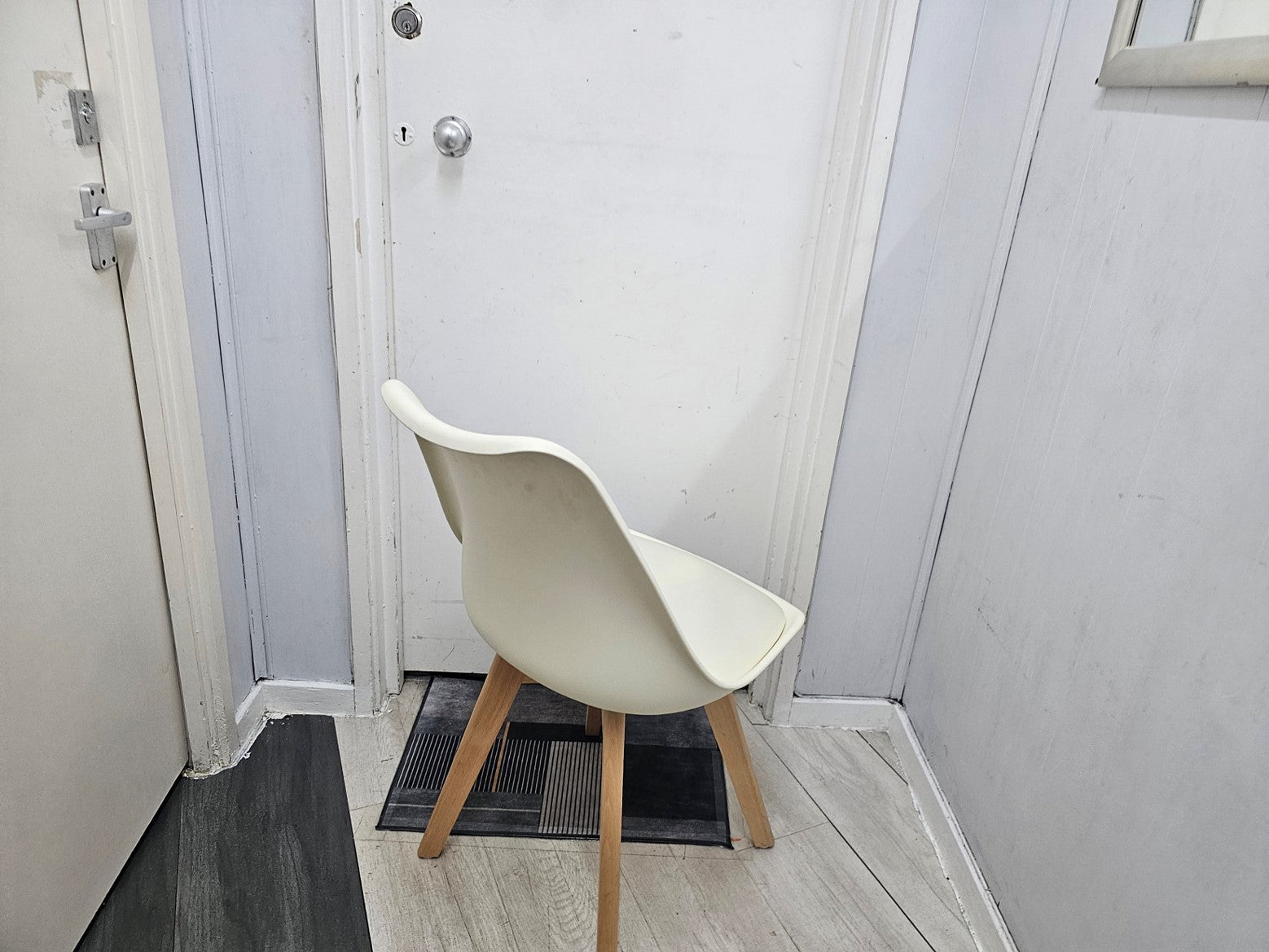 Back of white plastic chair in front of white door