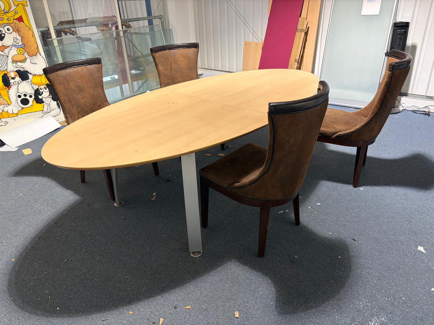 Secondhand maple-coloured boardroom table features a distinctive oval shape supported by four silver legs.