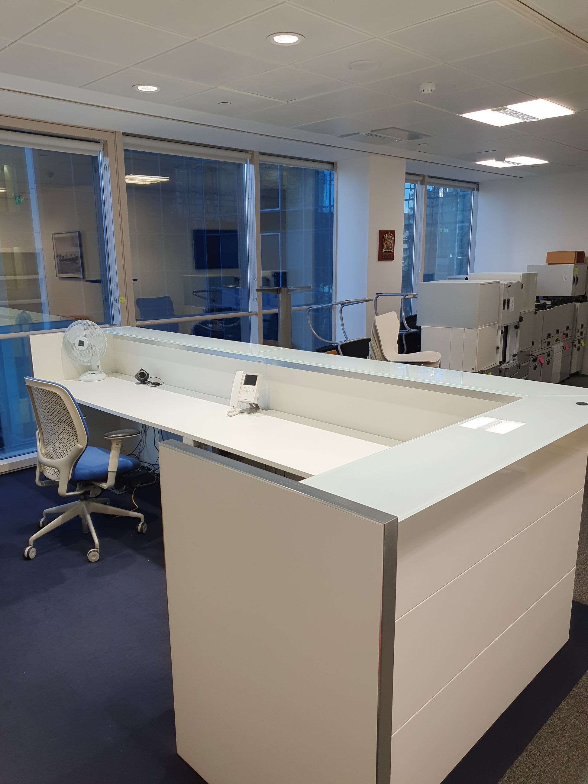 behind a white office reception desk with counter in office with chair