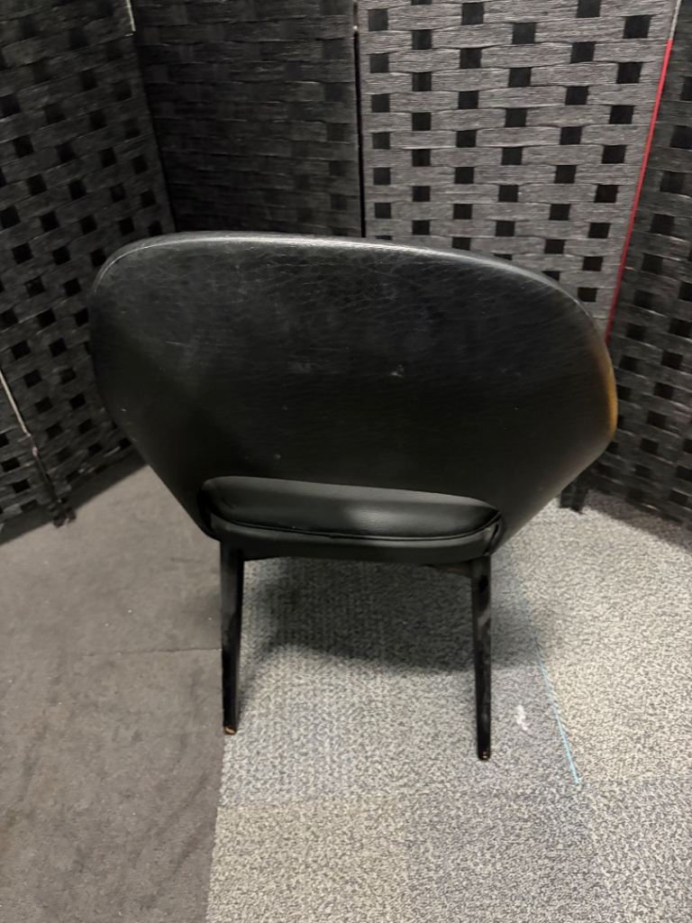 Used vintage inspired, open-back armchair features black faux leather upholstery