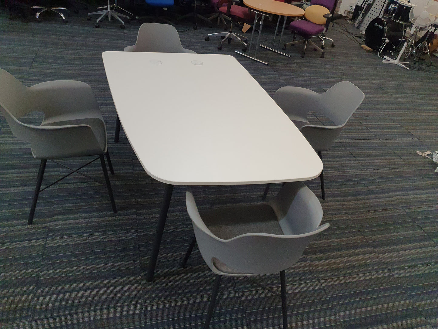 White office meeting table and four grey chairs in large room