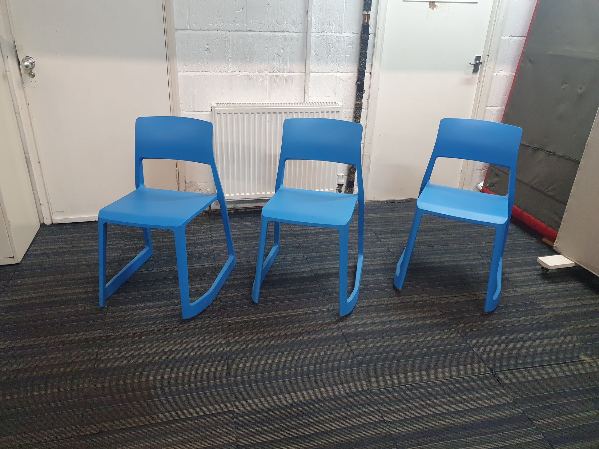 Three azure blue canteen chairs on carpet