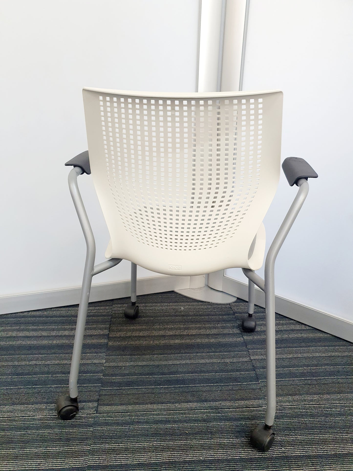 Back of perforated white stackable meeting chair