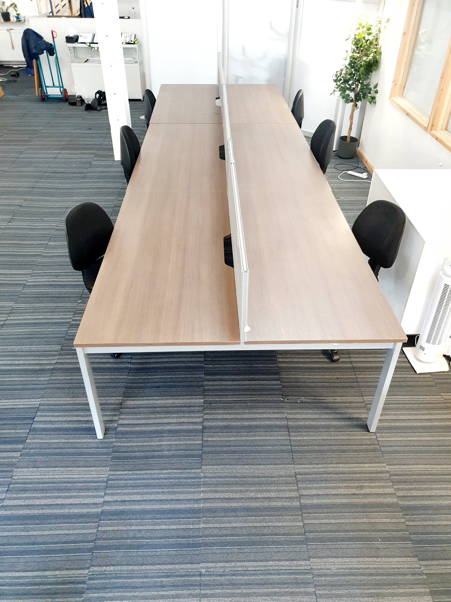 six black chairs tucked under walnut office tables
