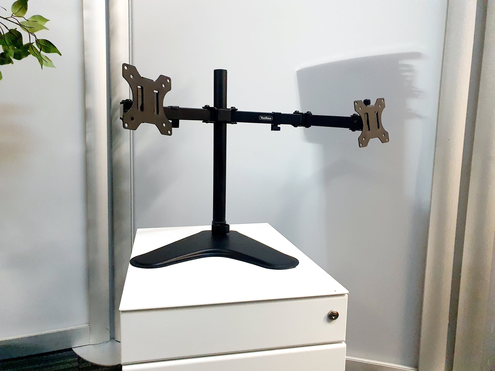 a black articulated Freestanding Desktop Monitor stand on white drawers
