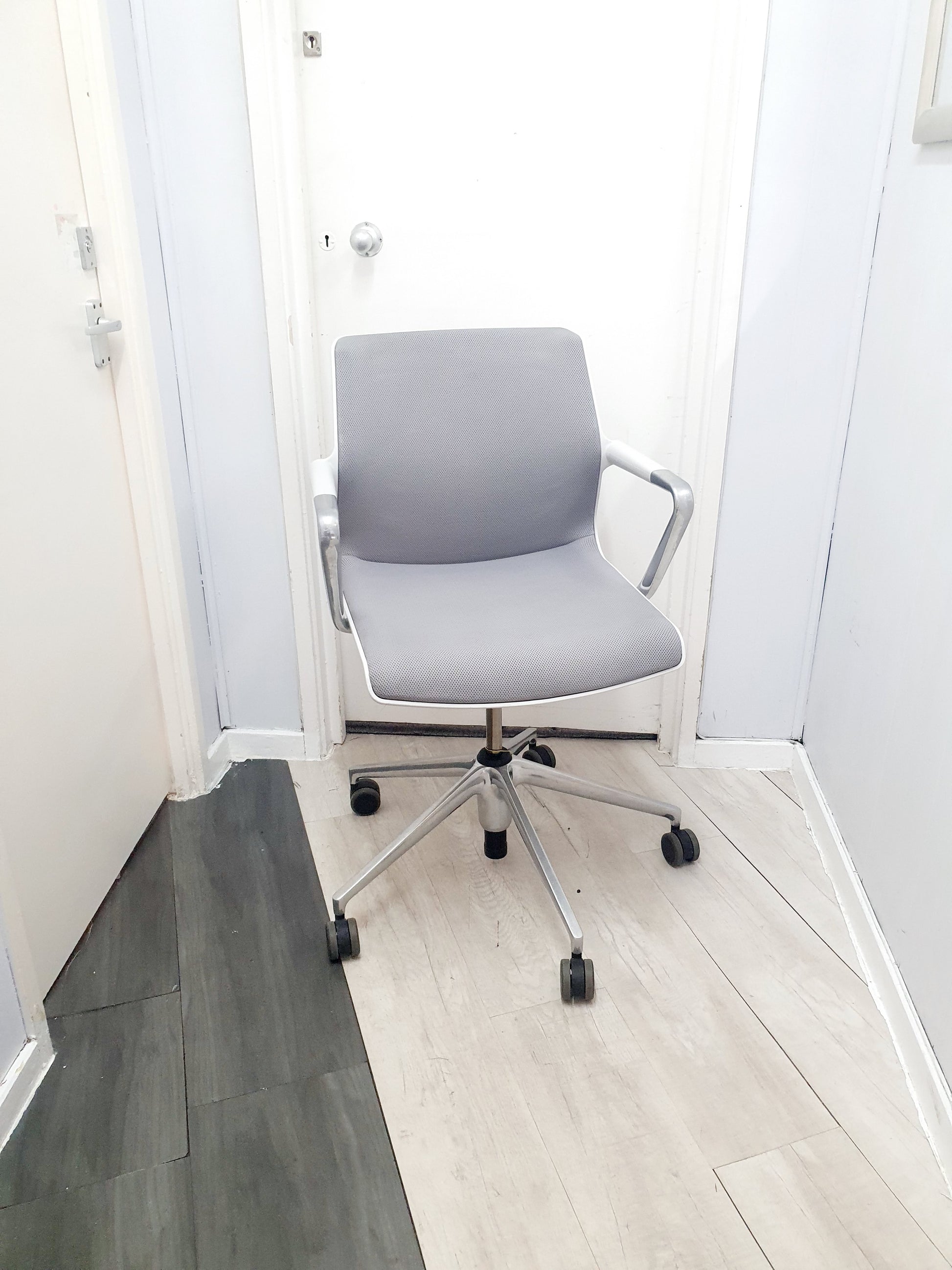 Grey office swivel chair on castors in front of 2 doors