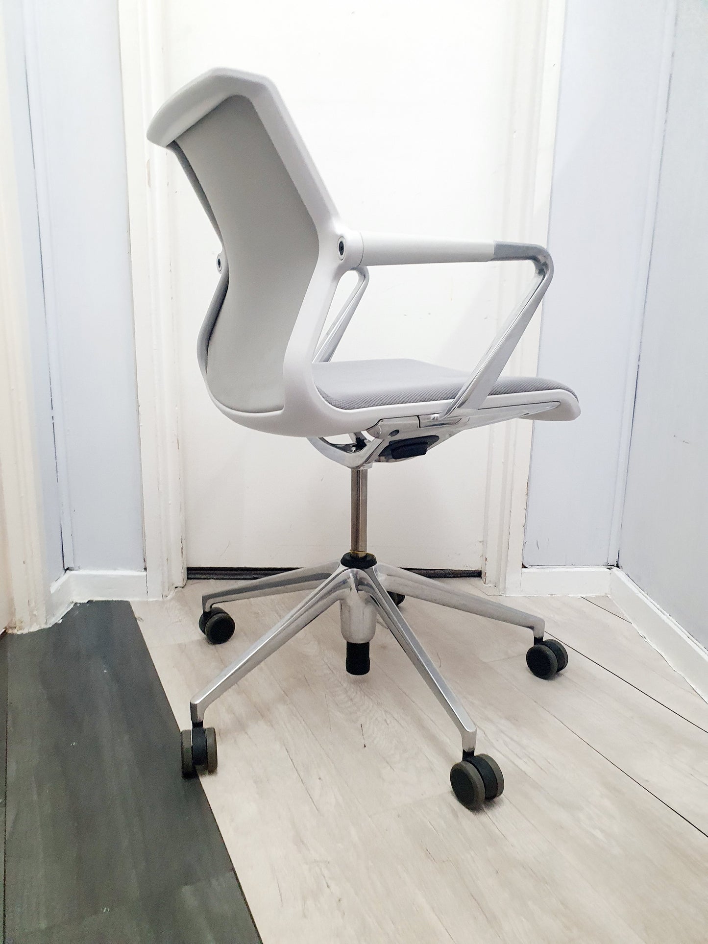 Mesh chair in grey and white in front of white door