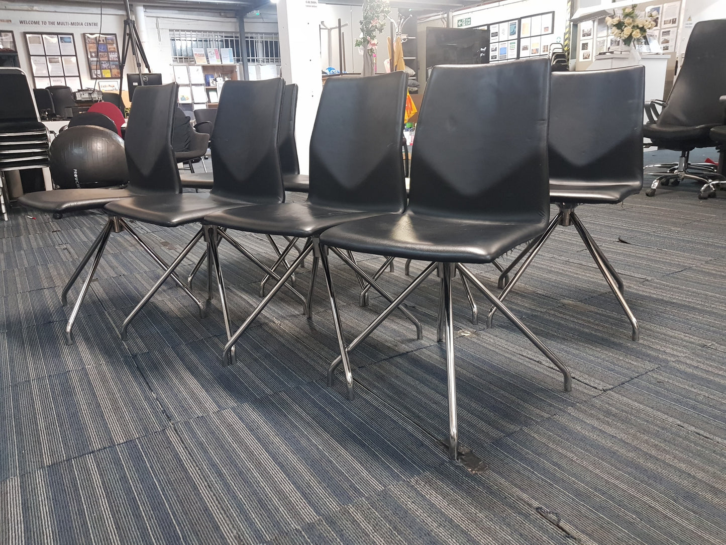 Eight black leather chairs on carpet
