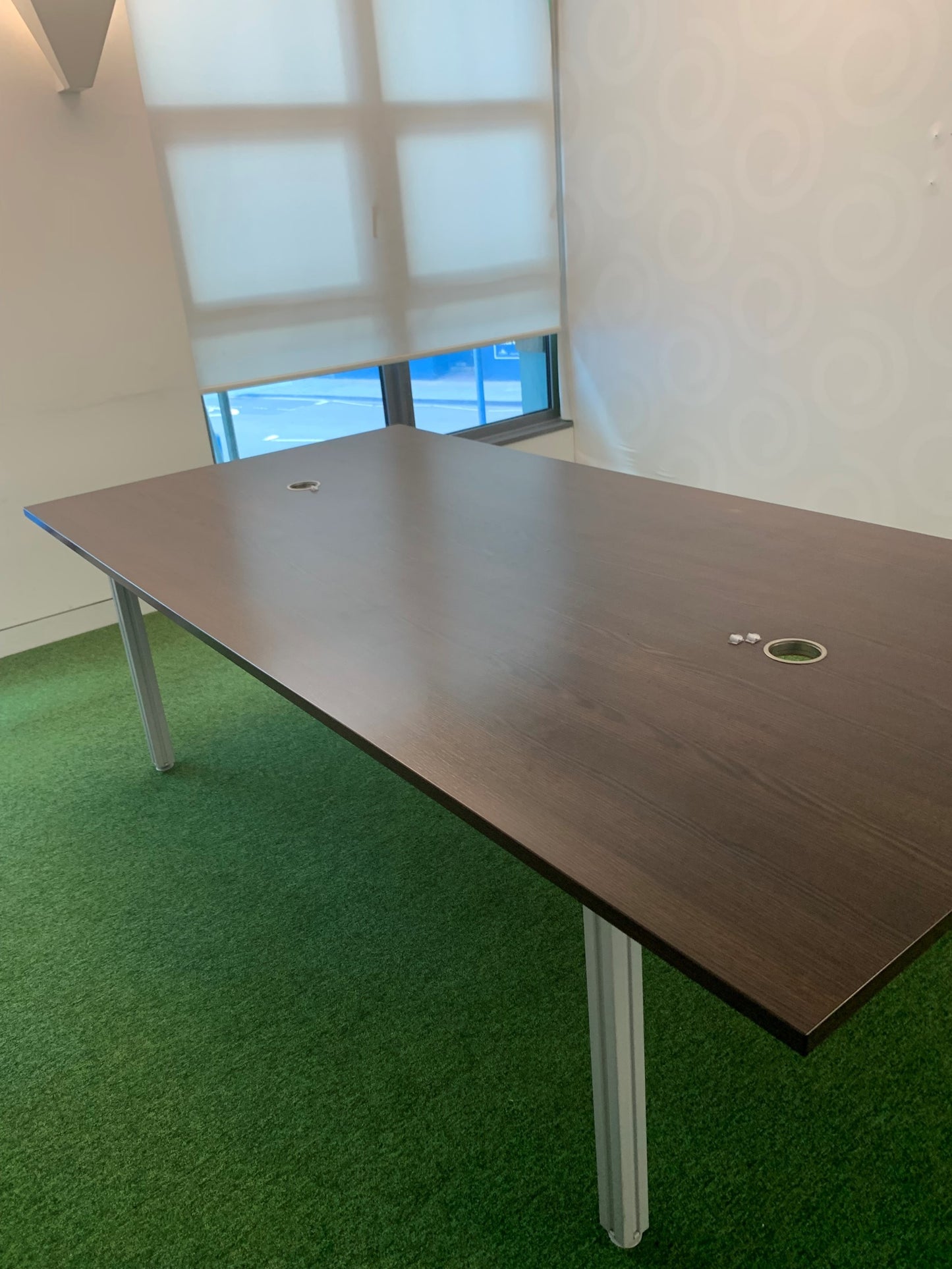 Brown boardroom table in room with large windows