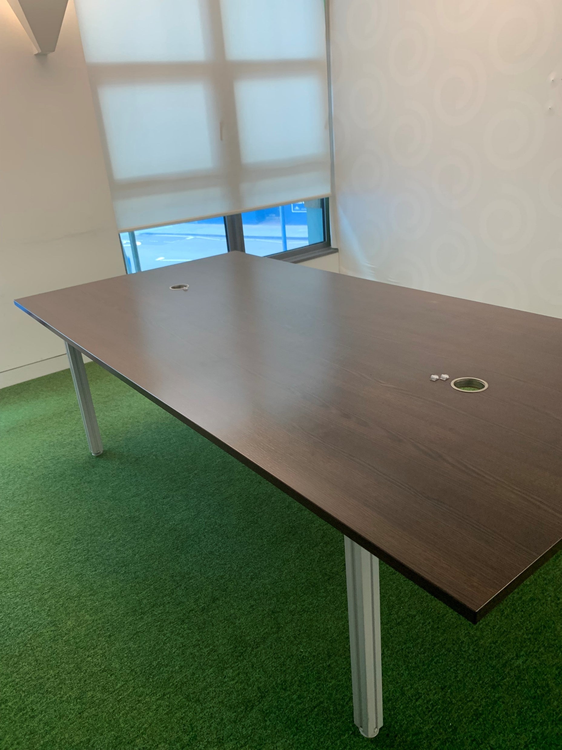 Brown boardroom table in room with large windows