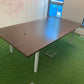 Walnut conference table on green carpet in room with large windows