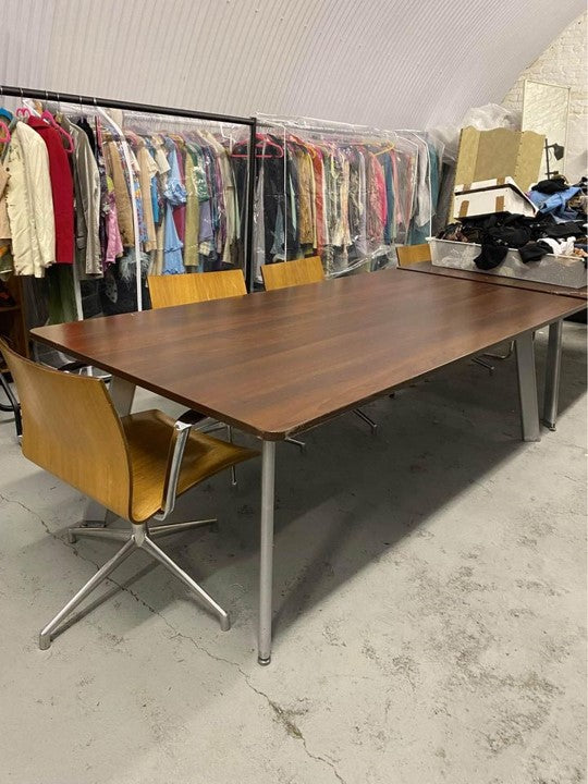 Walnut meeting table by open wardrobe of clothes