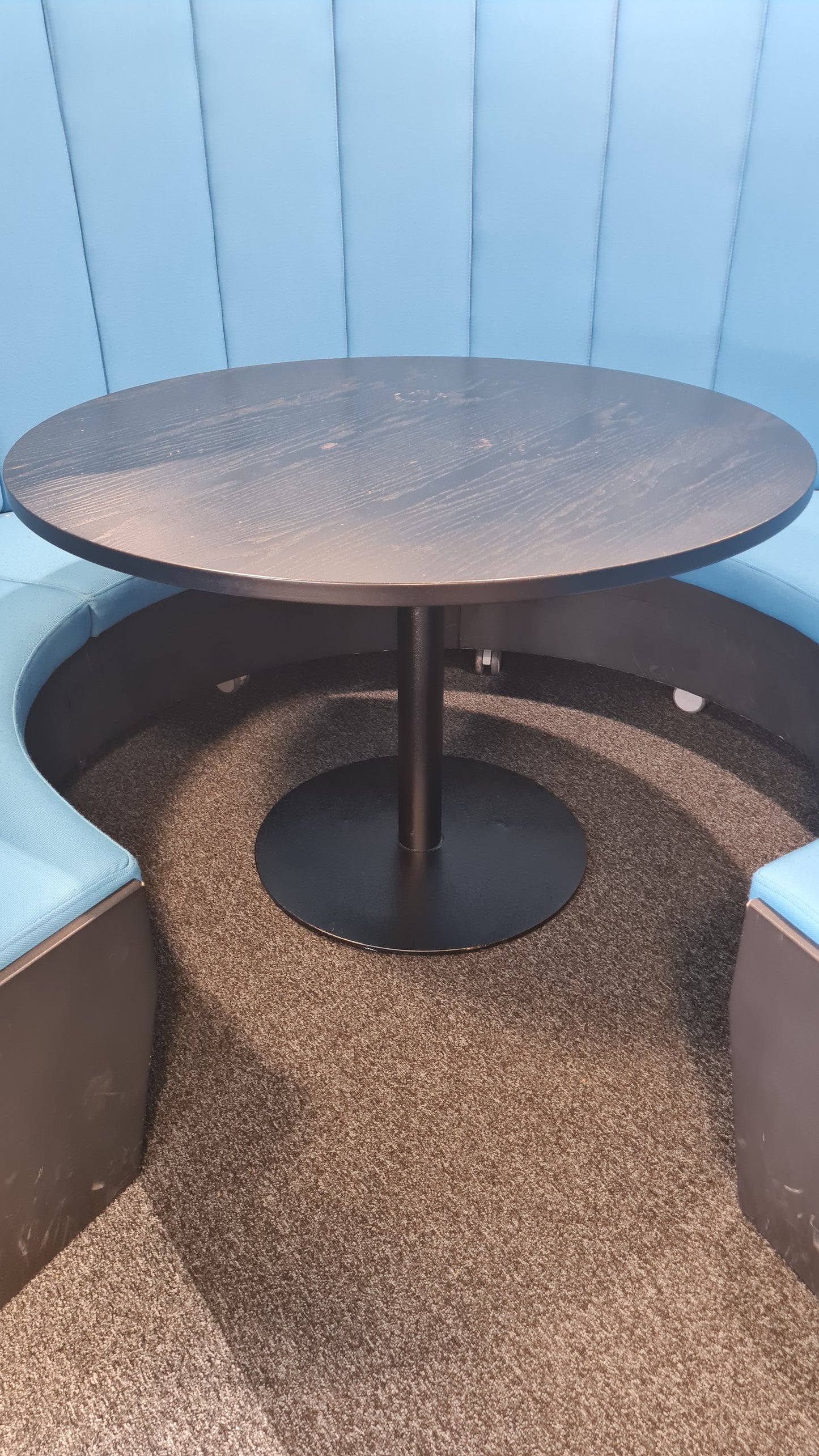 A black round table in a blue meeting pod