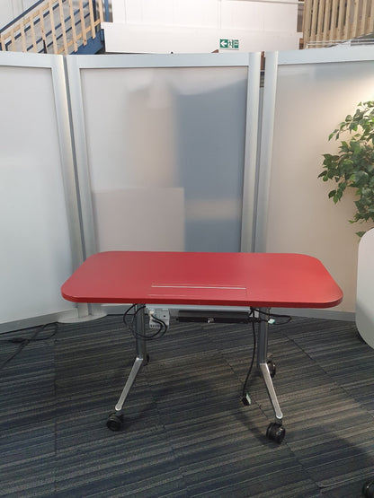 Red table on wheels in front of grey screen
