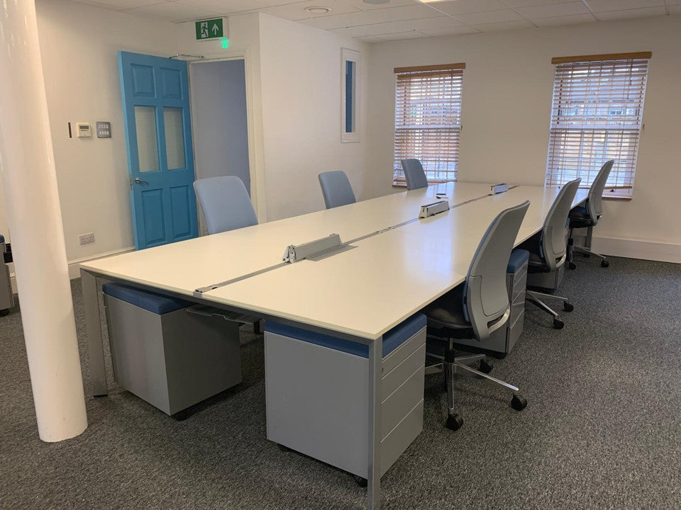 Banck of six office desks in White by office windows