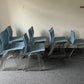 Multiple blue plastic dining chairs stacked in groups