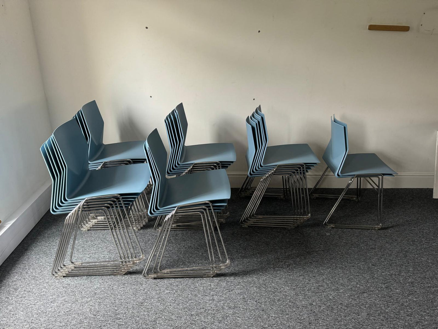 Multiple blue plastic dining chairs stacked in groups