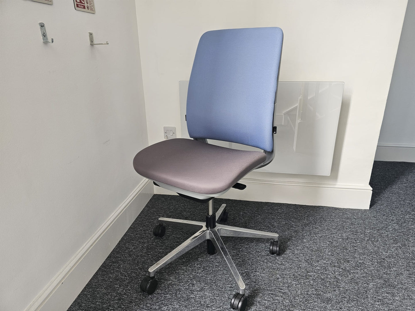 A blue and grey swivel admin chair in front of radiator