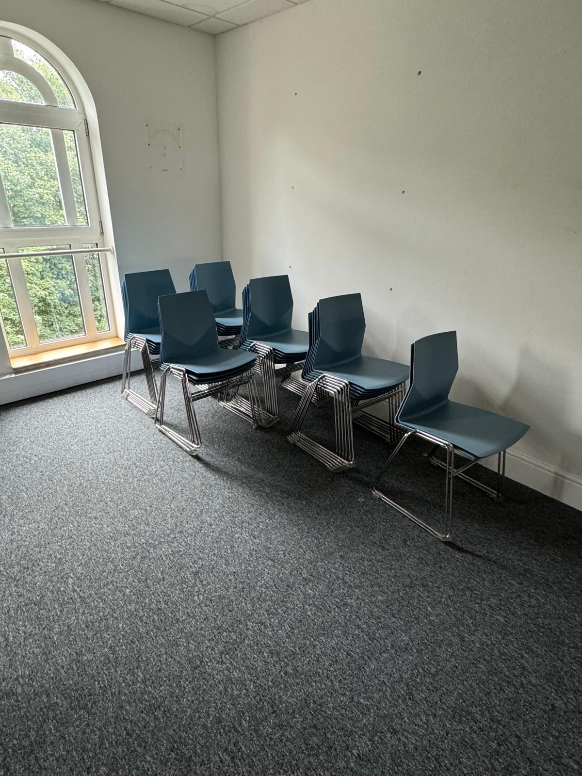 Six stacks of blue dining chairs on chrome legs