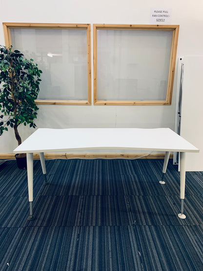 white office desk on carpet with green plant behind