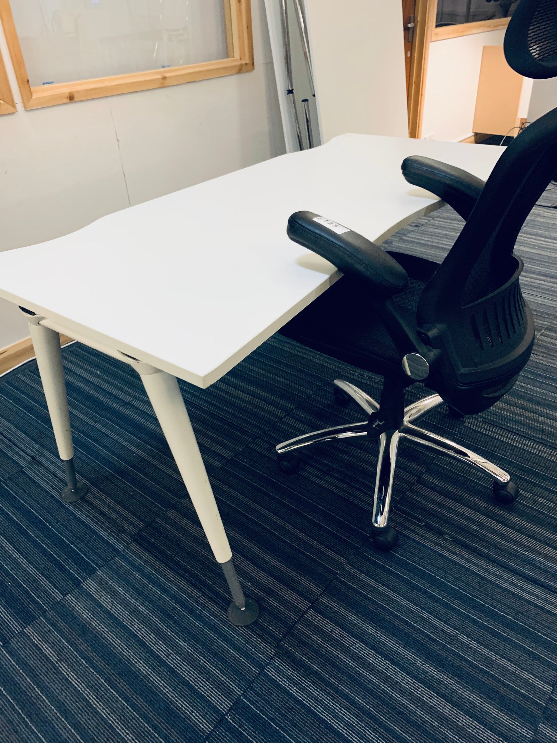 black ergonomic task chair tucked in to a white table