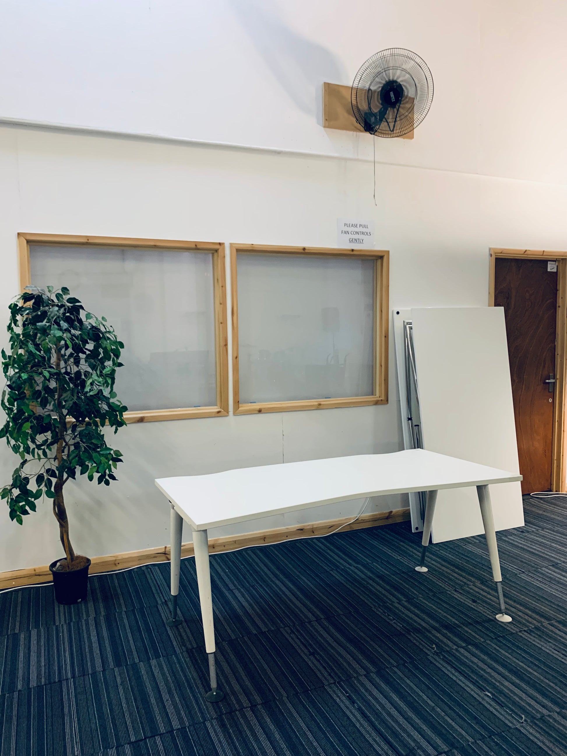 white workstation with folding desks folded on its right, green plant on its left