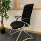 Black Sitland cantilever chair, left, tall green plant