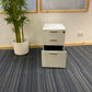 three drawer cabinet with open bottom drawer and tall green plant