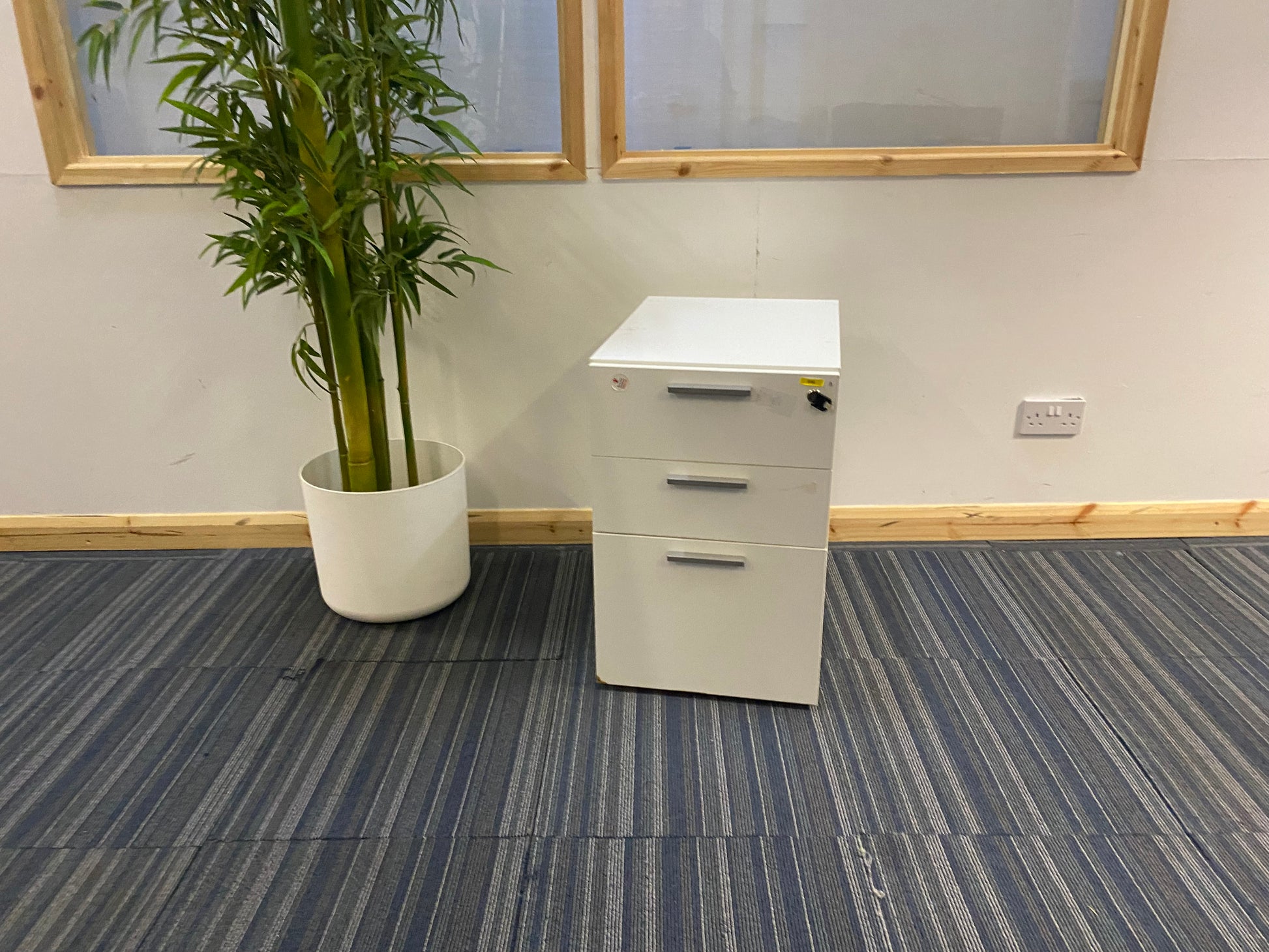 White three drawer small filing cabinet and tall green plant