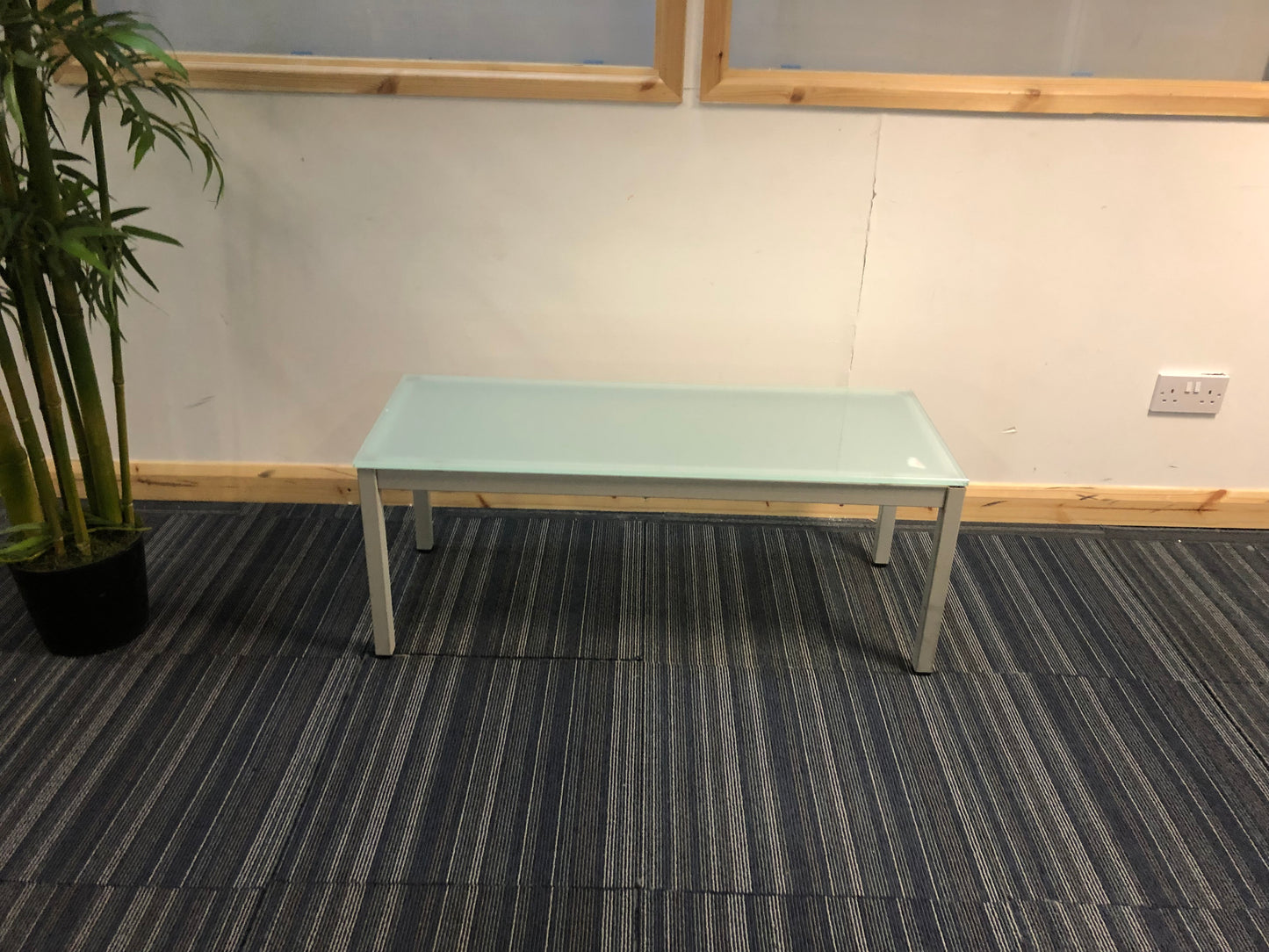 blue glass office reception table centre, top left green tall plant