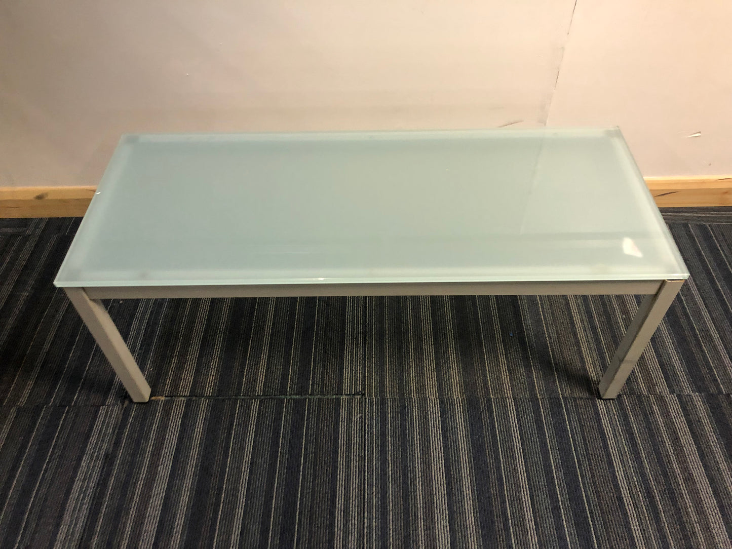 tabletop of blue glass office reception table centre, top left green tall plant