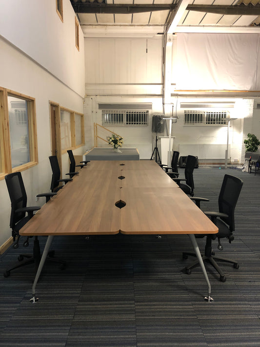 Walnut office bench desks with six black chairs in large hall