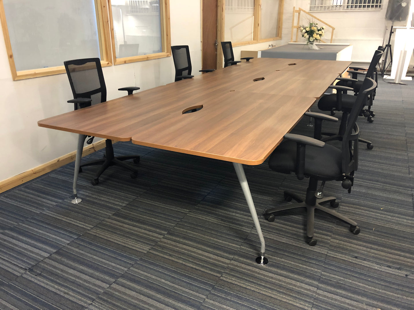 Walnut office bench desks with six black chairs