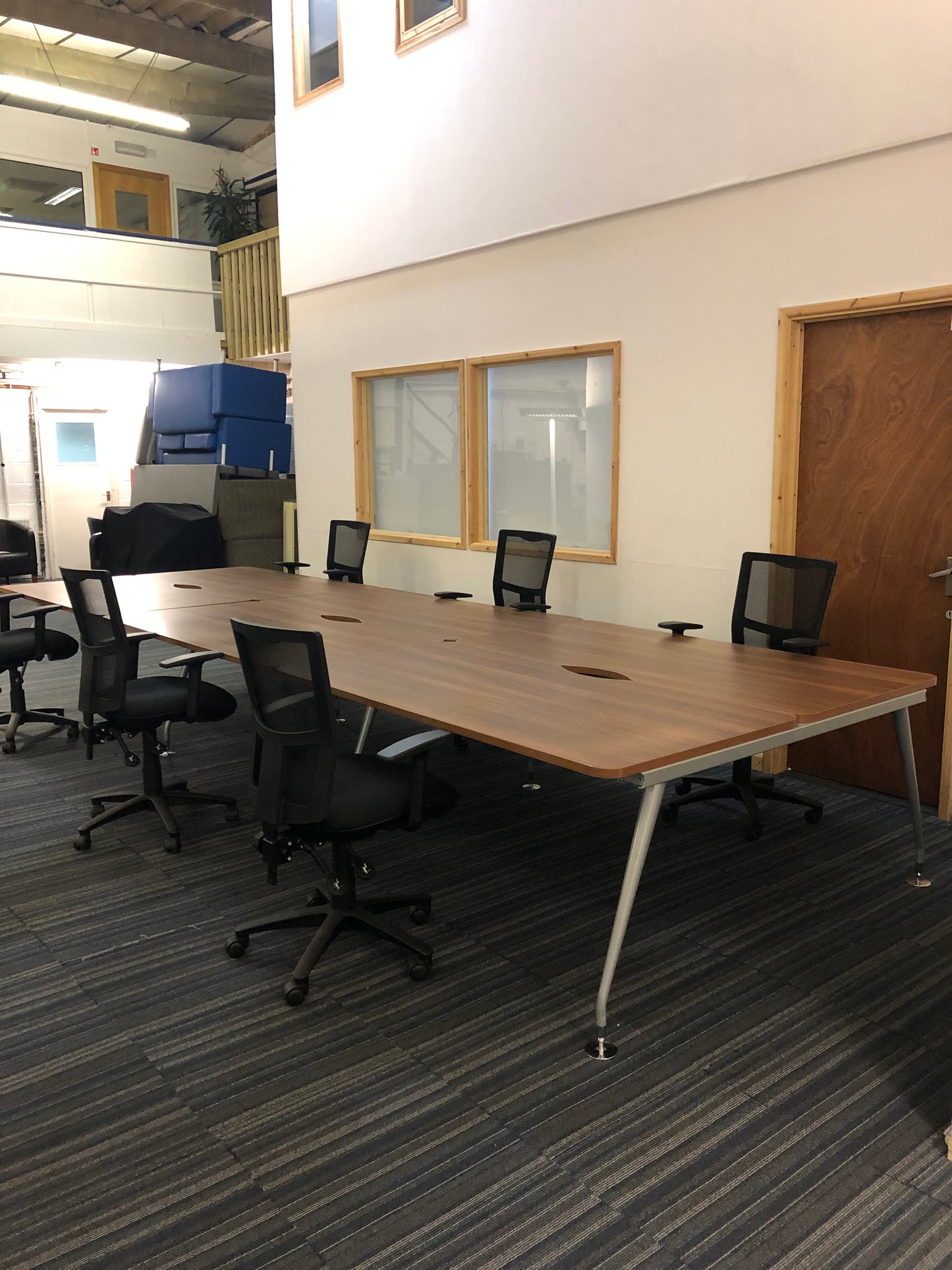 Walnut office benching workstations with six black chairs