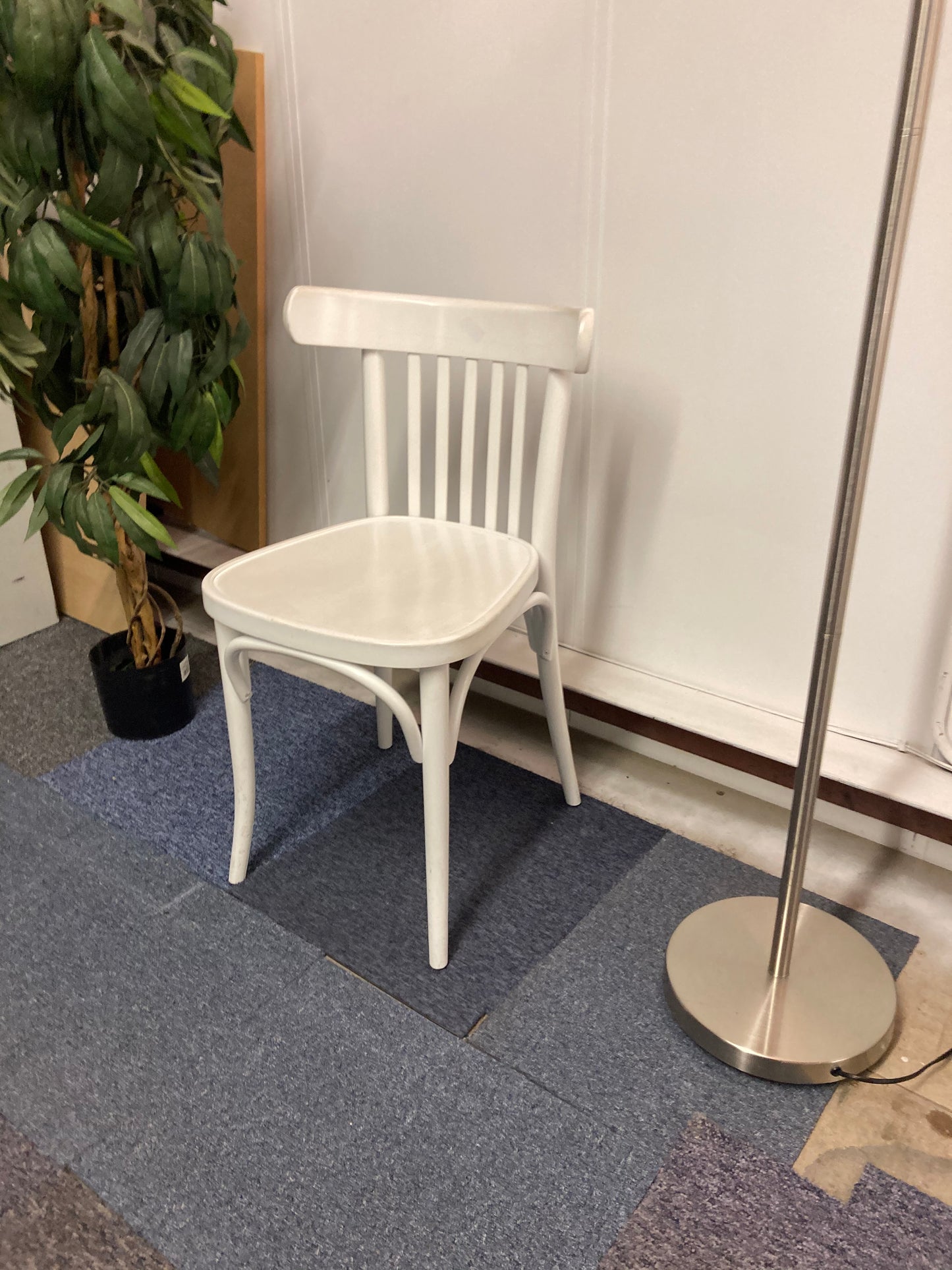 Left, tall green plant, centre, Waiting area chair in white, Right, chrome light stand