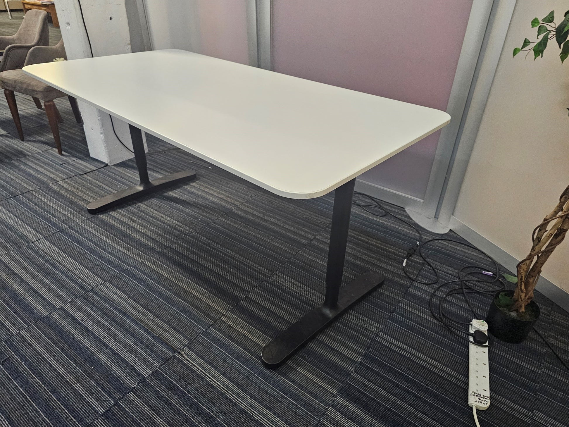 White office table with black legs on blue carpet