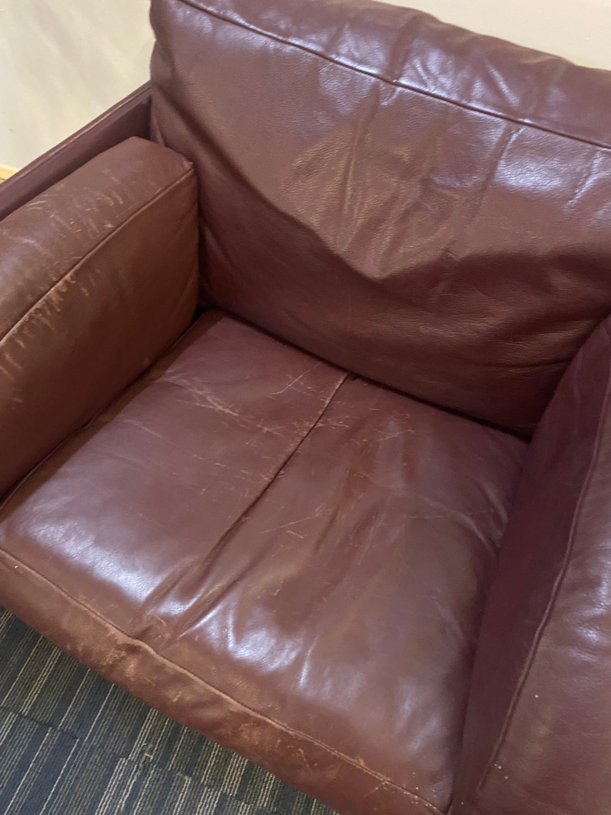 damaged seat of leather single armchair sofa with plant