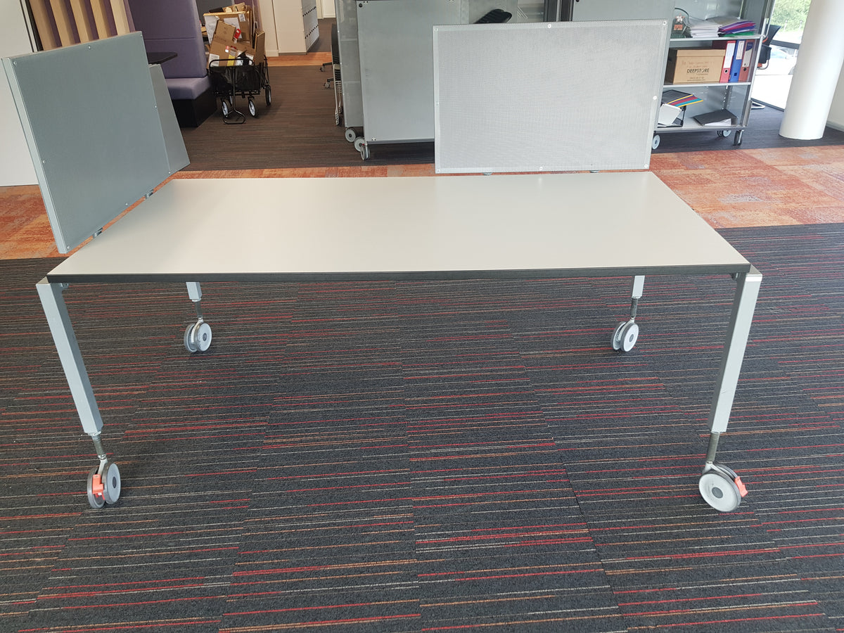 A mobile Senator home office desk table with a beige tabletop and white metal frame on casters.