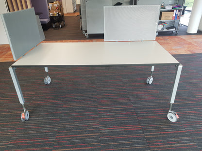 A mobile Senator home office desk table with a beige tabletop and white metal frame on casters.