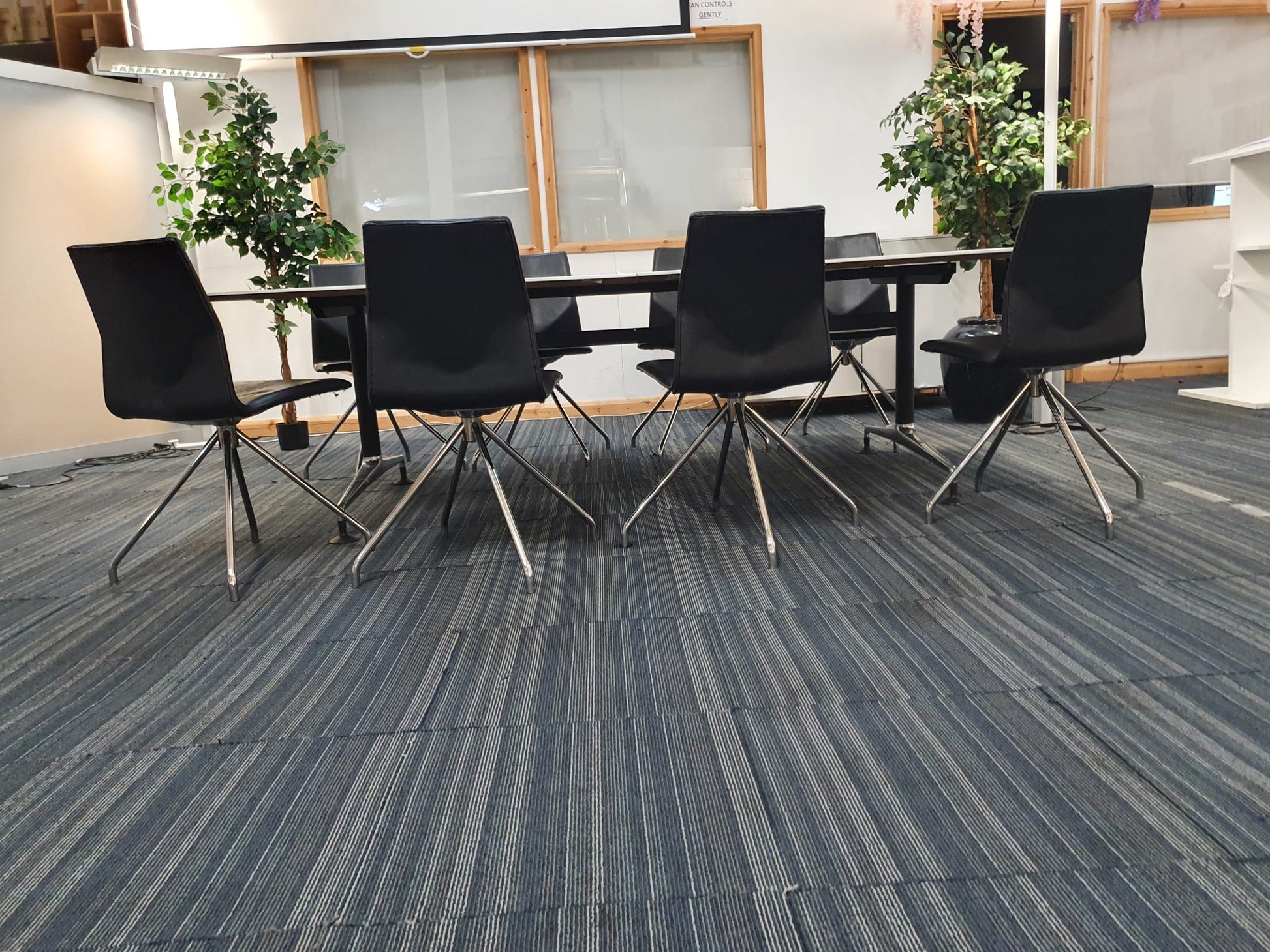 Eight black leather office chairs with stick legs at meeting table