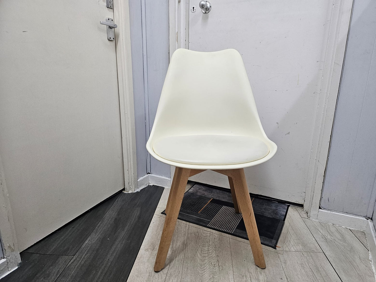 White dining chair with padded seat in front of door