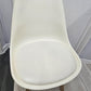 Padded seat base of white plastic chair in front of white door