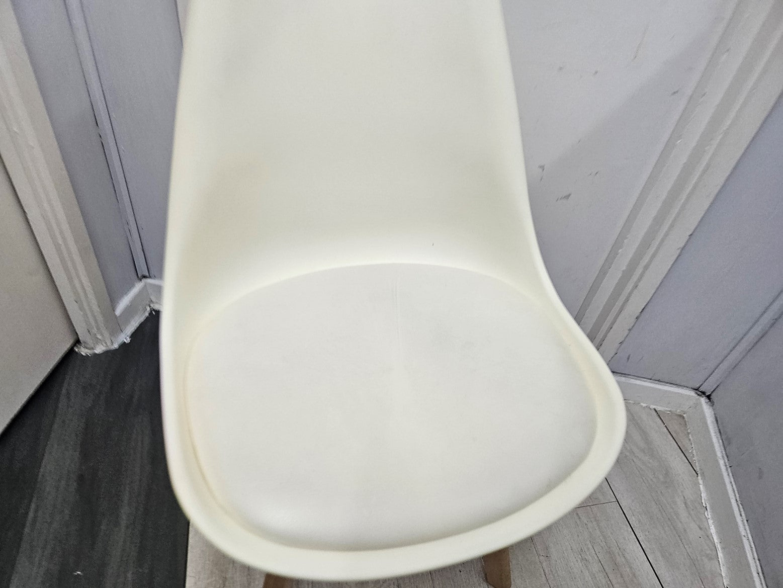 Padded seat base of white plastic chair in front of white door