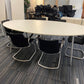 Oval white conference room table and 6 black cantilever chairs, and multiple swivel desk chairs