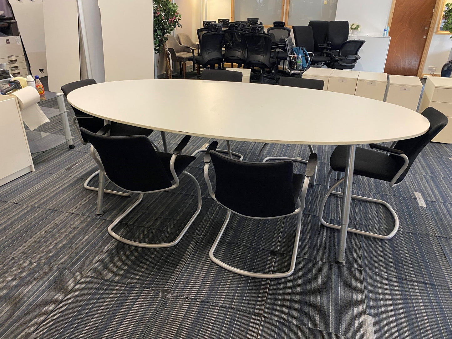 Oval white conference room table and 6 black cantilever chairs, and multiple swivel desk chairs