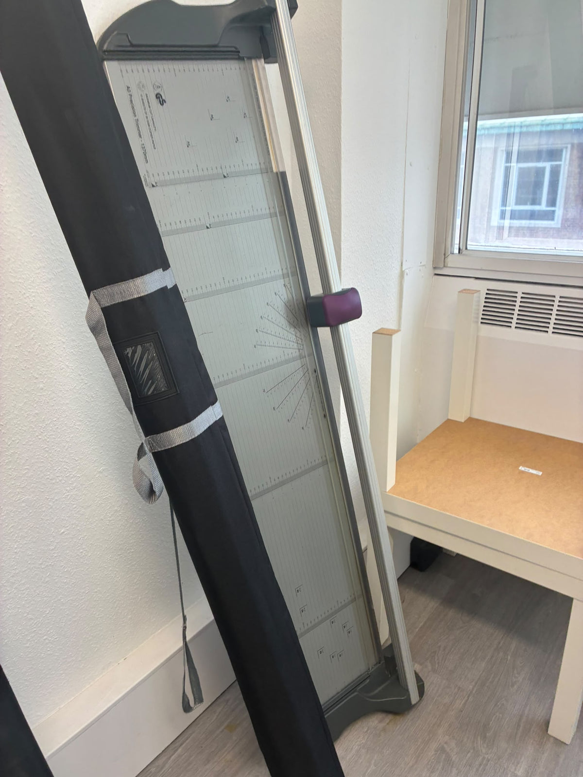 a glass panel and paper cutter, shown standing in a room next to a window 