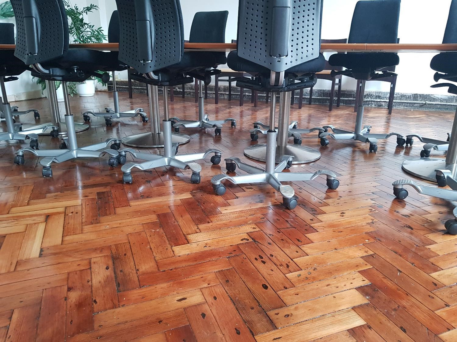 Black desk chairs on wheels at large brown office table