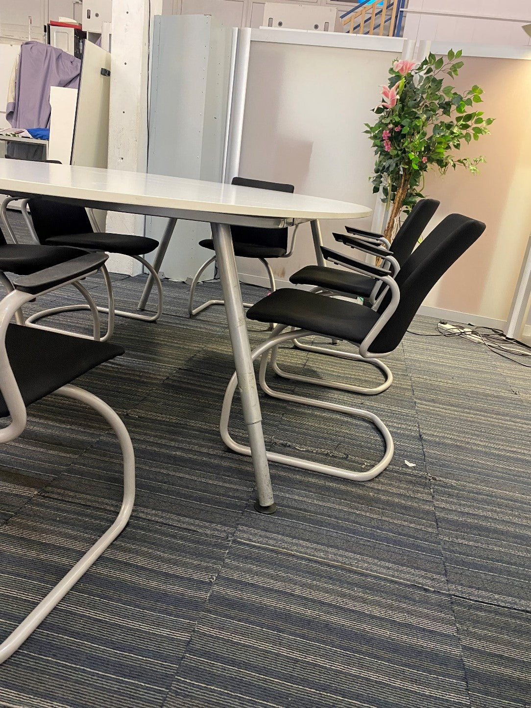 Black cantilever chairs round a white Oval white conference room table