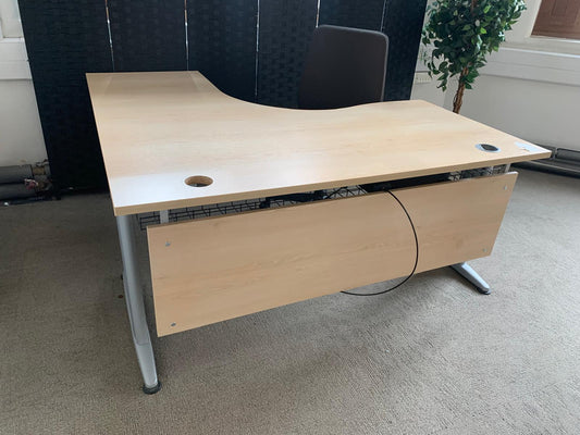 L shape desk on carpet with a black screen  plant and chair
